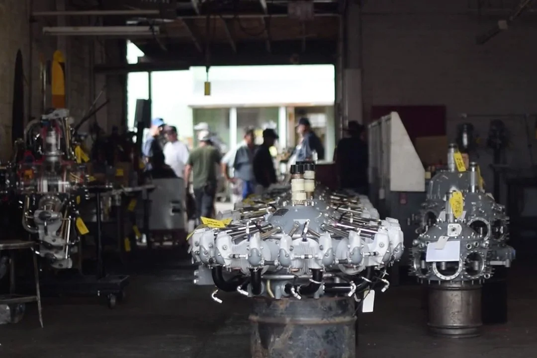 Industrial workshop with aircraft engine components on display and people examining in the background.