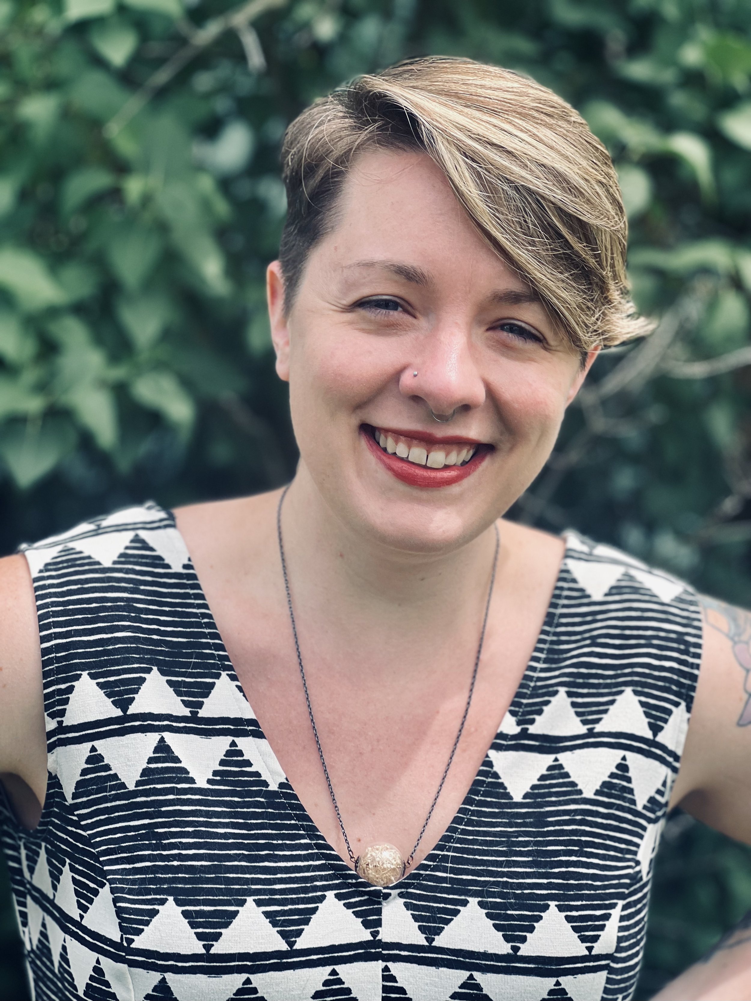Portrait of a beautiful smiling woman with blurred green foliage in the background