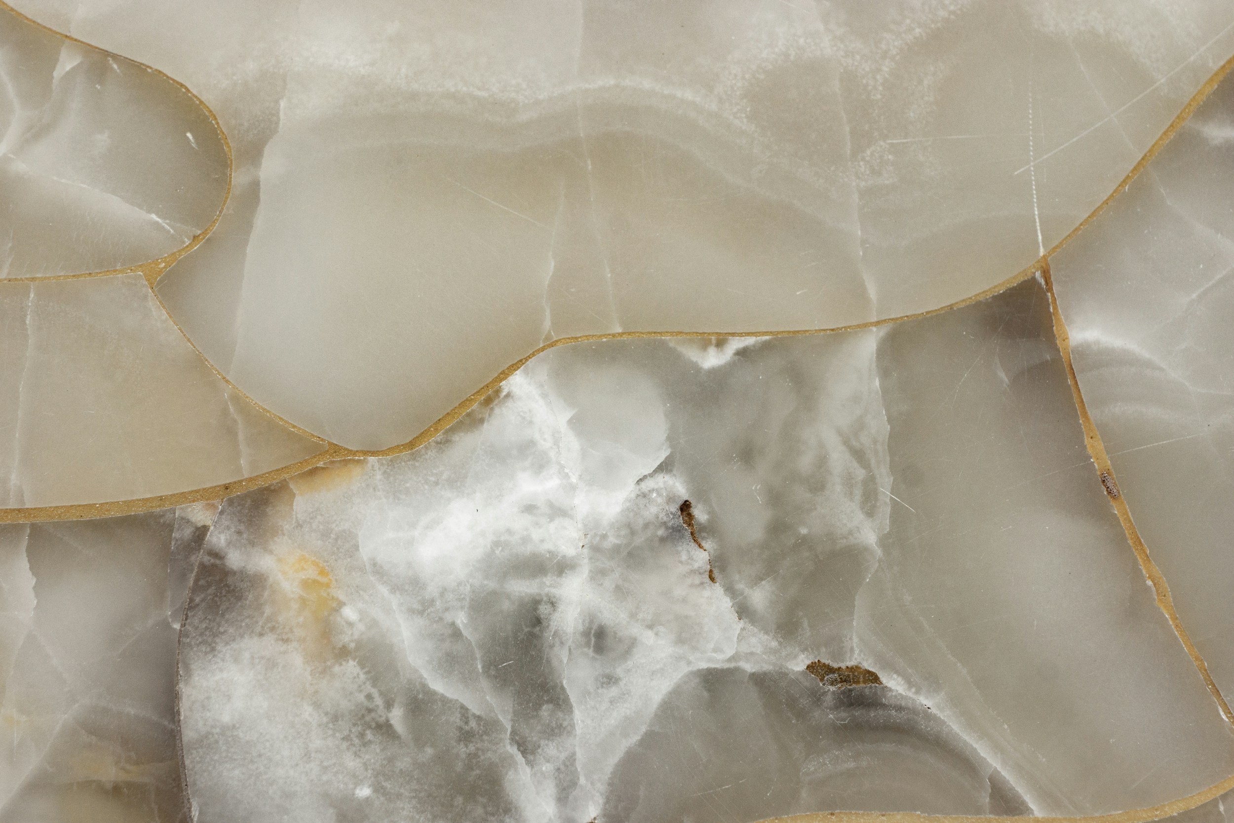Close-up of cracked and broken marble or stone surface with visible fractures and irregularities.