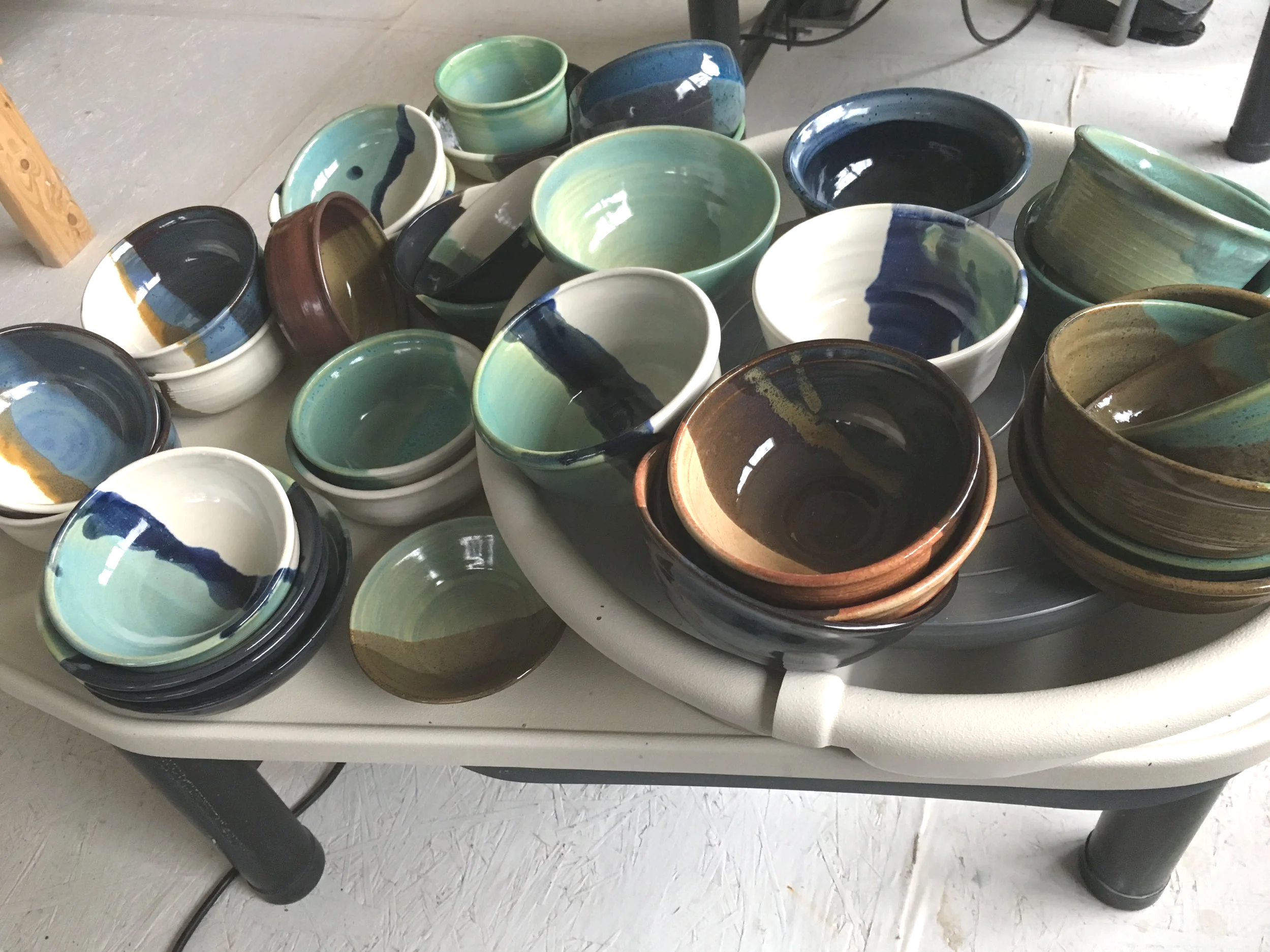 A collection of handmade ceramic bowls with various glazes, arranged on a white tray on a table.
