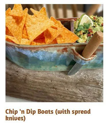 A bowl of tortilla chips with a side of guacamole and lime wedges.
