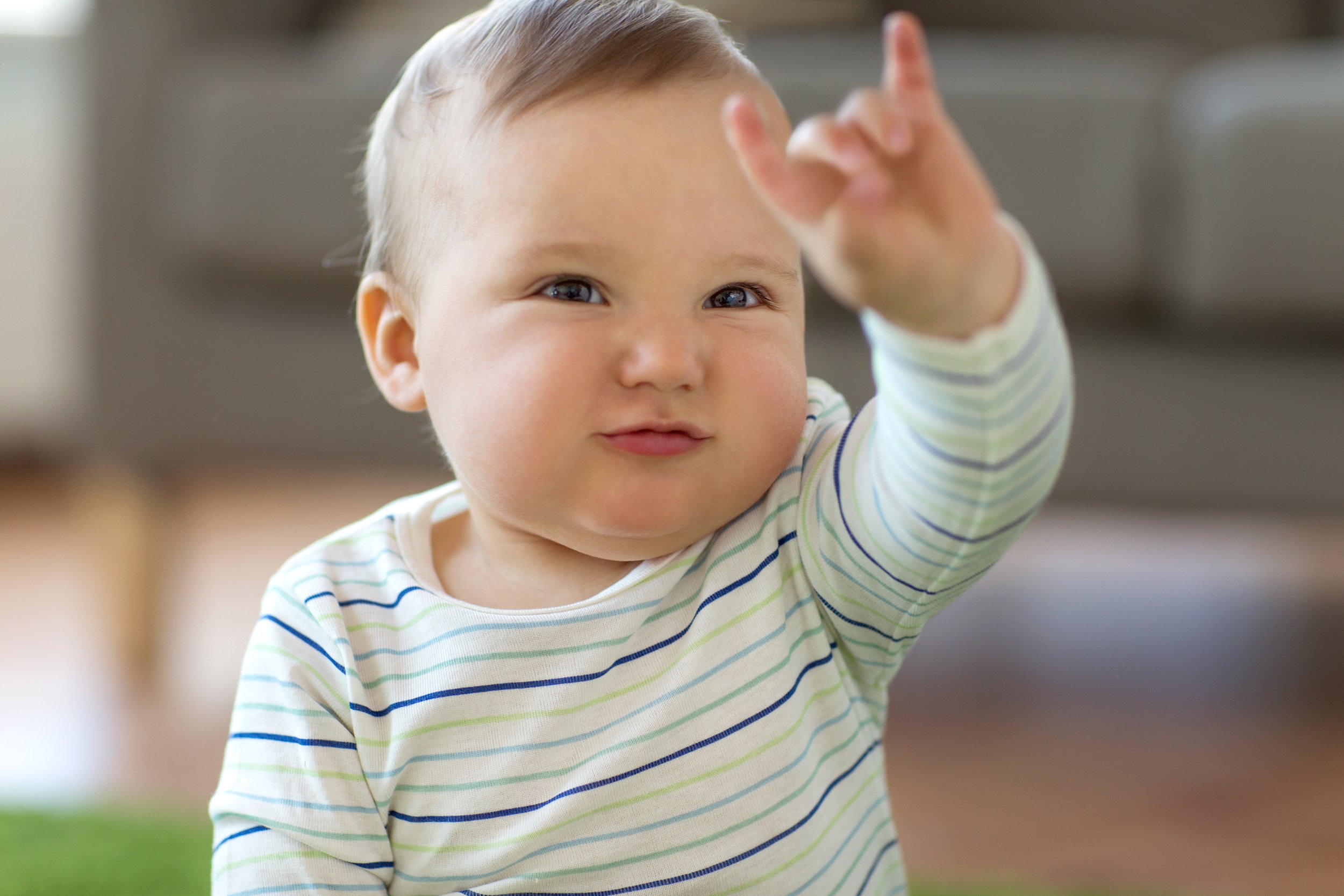 A baby practicing manual babbling by reaching out and gesturing with their hand, illustrating the early stages of sign language development.