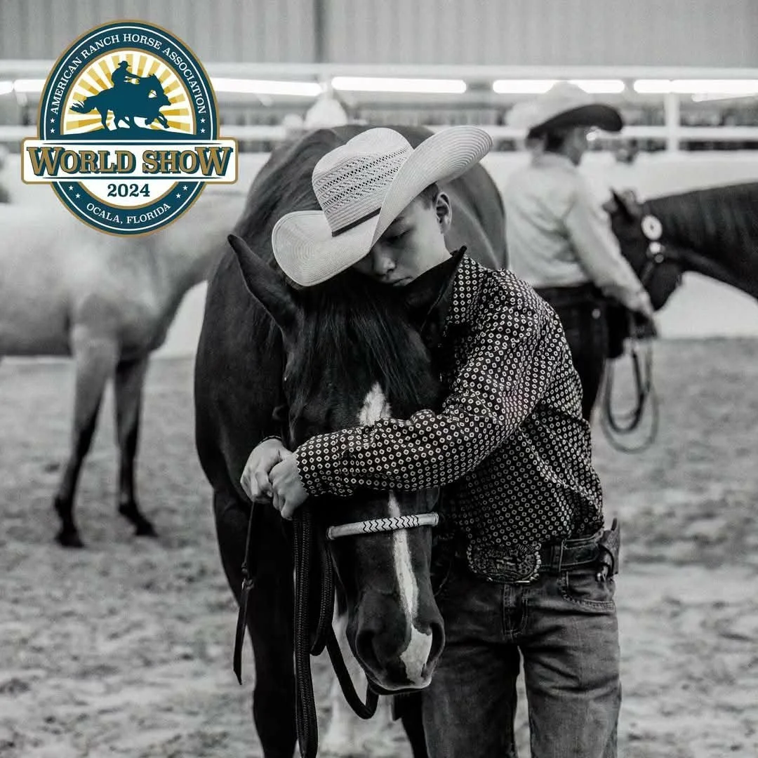 A young child wearing a cowboy hat hugging a horse at an indoor equestrian event. The image is in black and white with a logo in the top left corner for the 2024 World Show organized by the American Ranch Horse Association, held in Ocala, Florida.