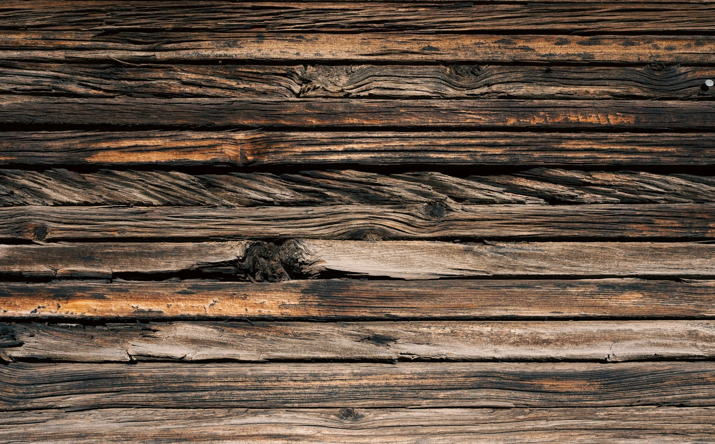 Close-up of weathered wooden planks with visible grain, knots, and cracks.