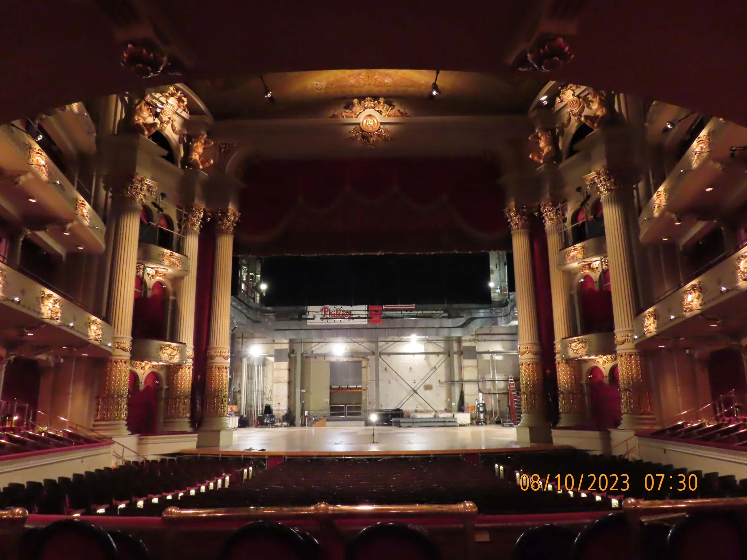 Large theater, from back of audience to stage, with high column and several balconies. 