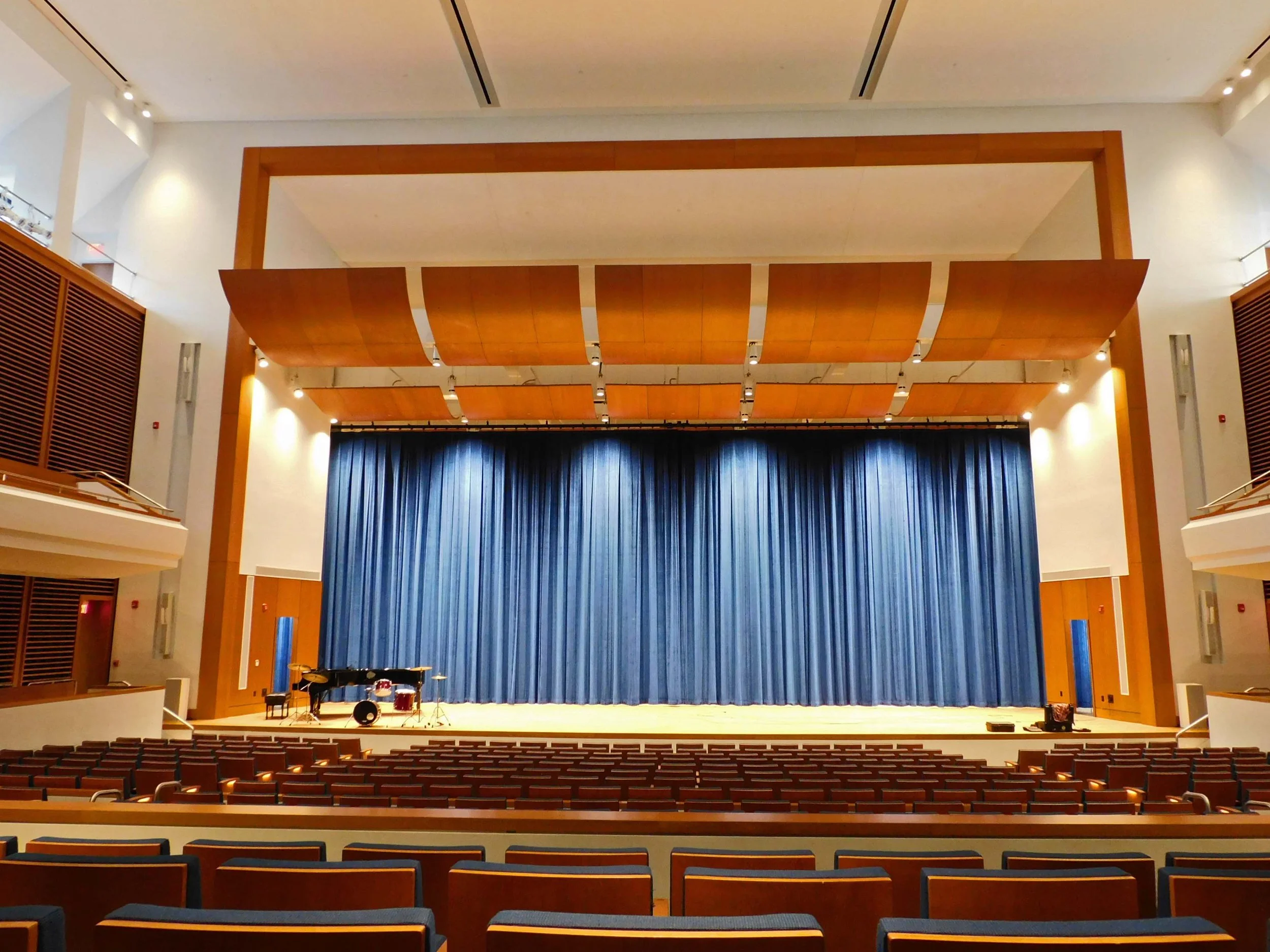 Large theater with orange acoustic panels and blue curtain. 