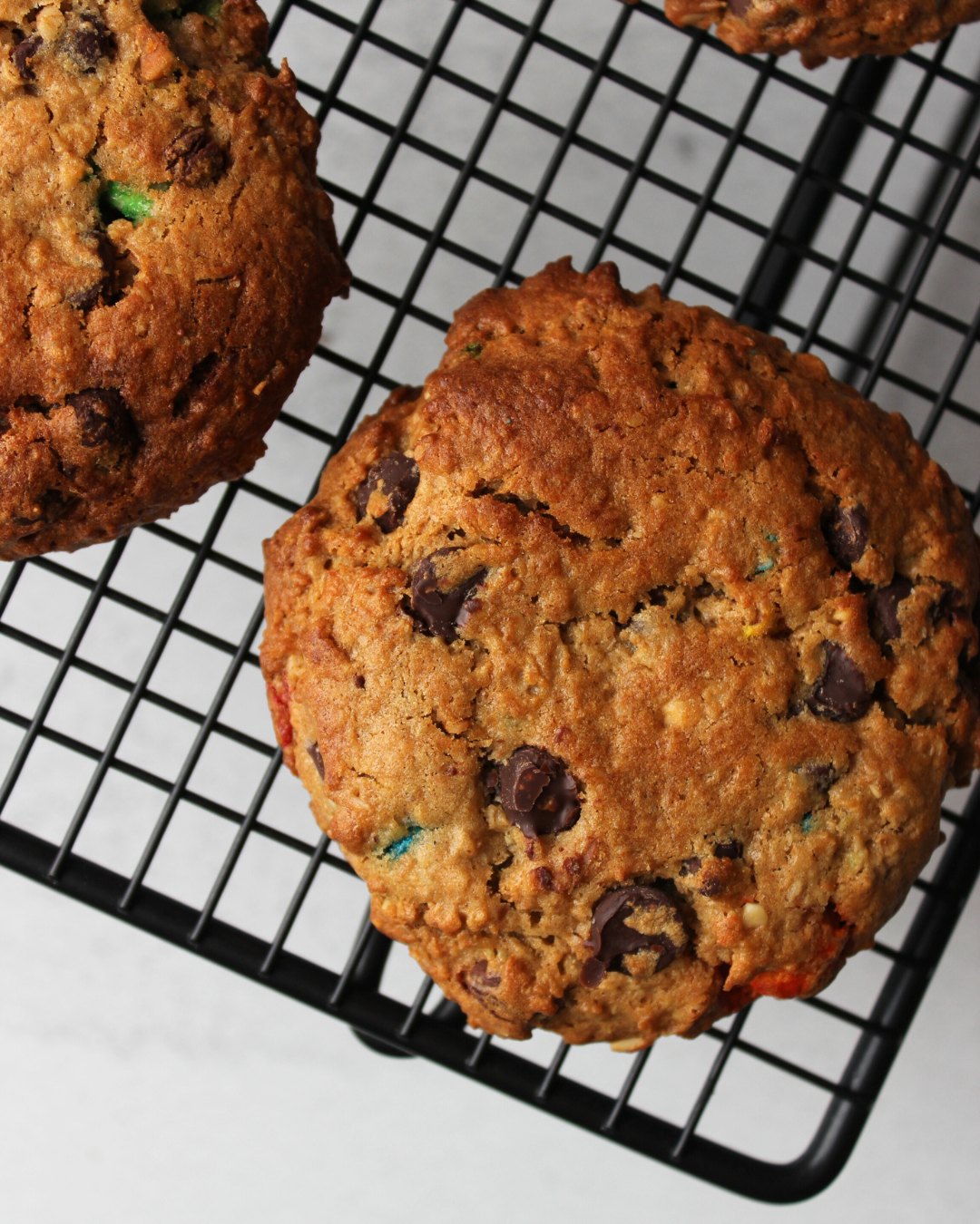 Close-up of two chocolate chip cookies on a black cooling rack.