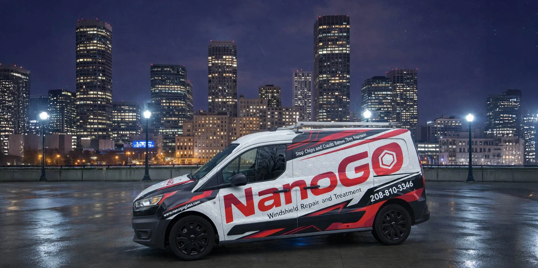 Nighttime cityscape with illuminated skyscrapers and a Nanoglas windshield repair van parked on a wet rooftop.