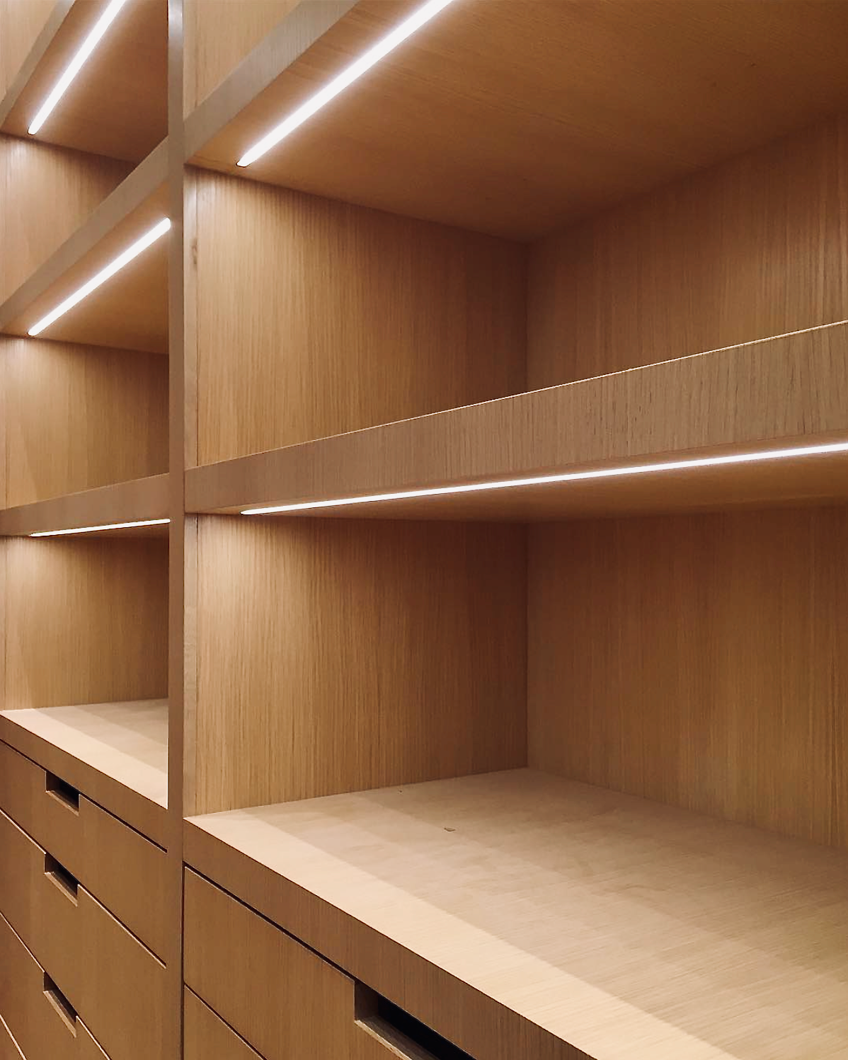 Prior fabrication experience.
White oak closet with open shelving, drawers, and integrated linear lighting.