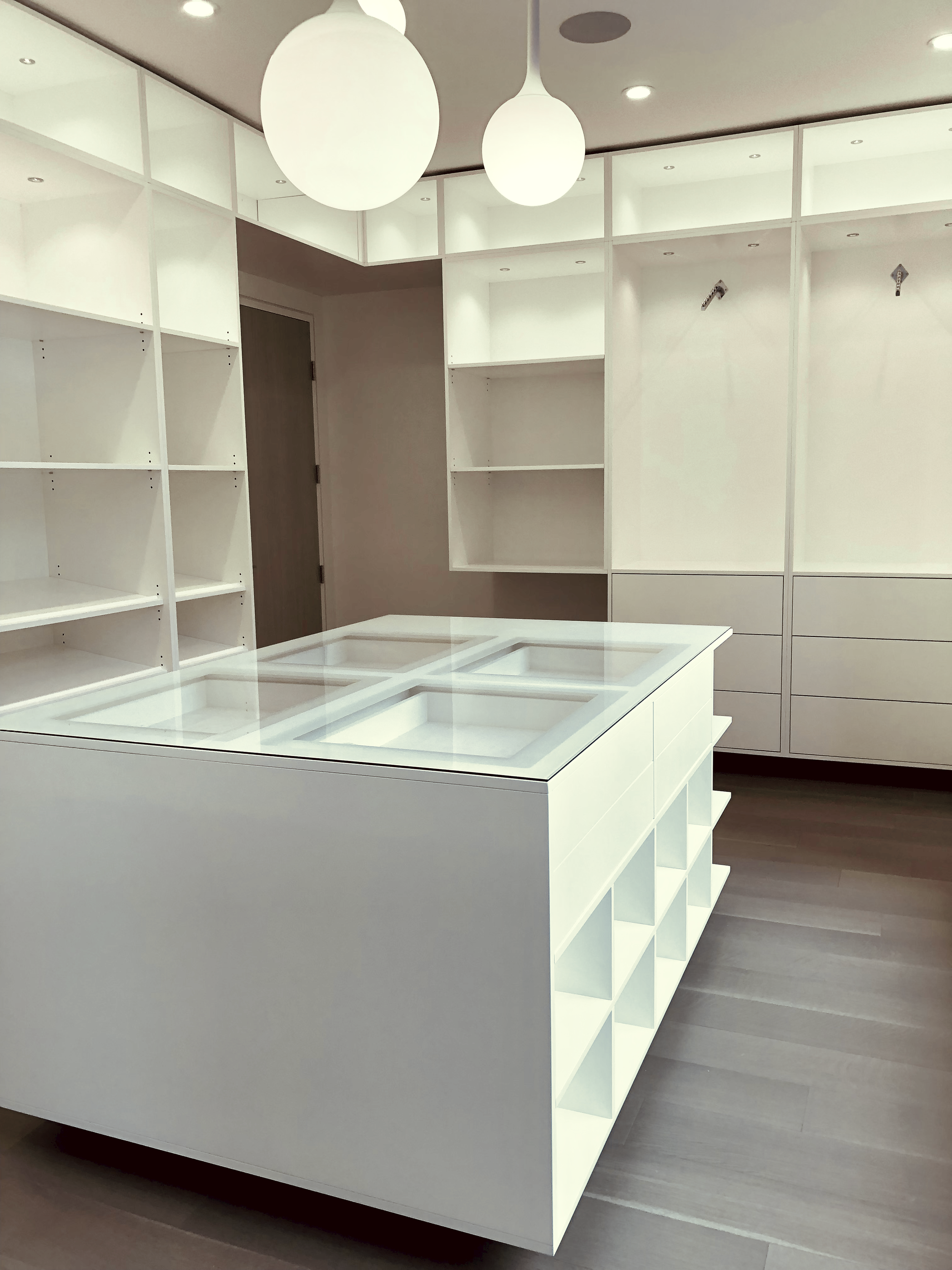 Prior fabrication experience.
White dressing room island with open shelving and drawers.