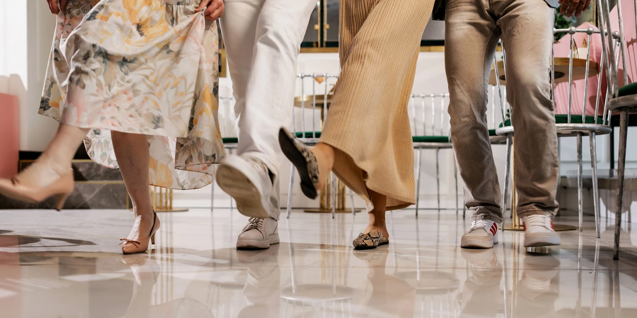 Close-up of three people dancing, focusing on their legs and shoes in a stylish, modern room.