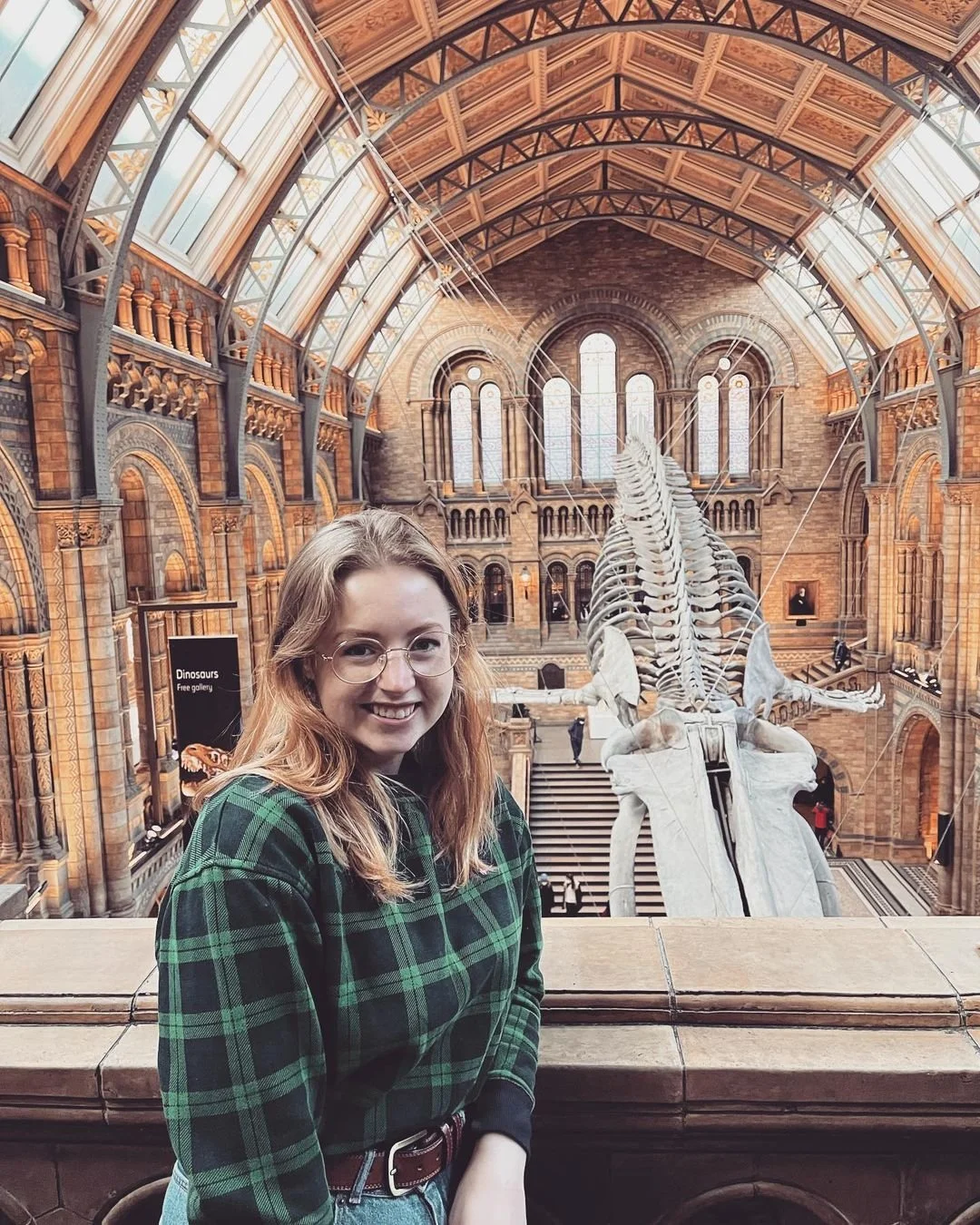 A woman wearing a green jumper stood in front of a large whale skeleton.