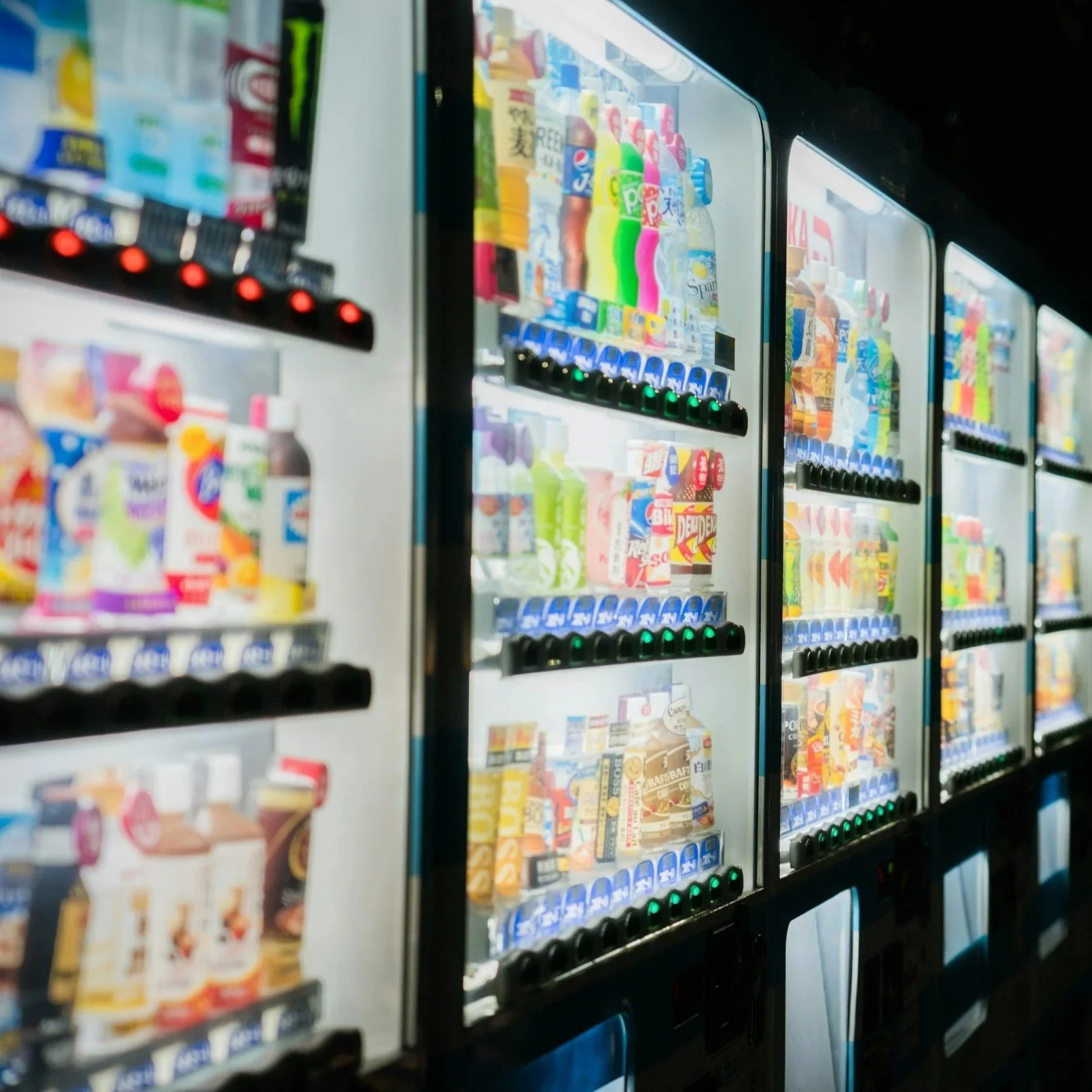 four illuminated vending machines with dark background