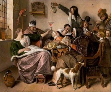 A social scene of people gathered around a table enjoying drinks and food, with a dog present, in a rustic interior.