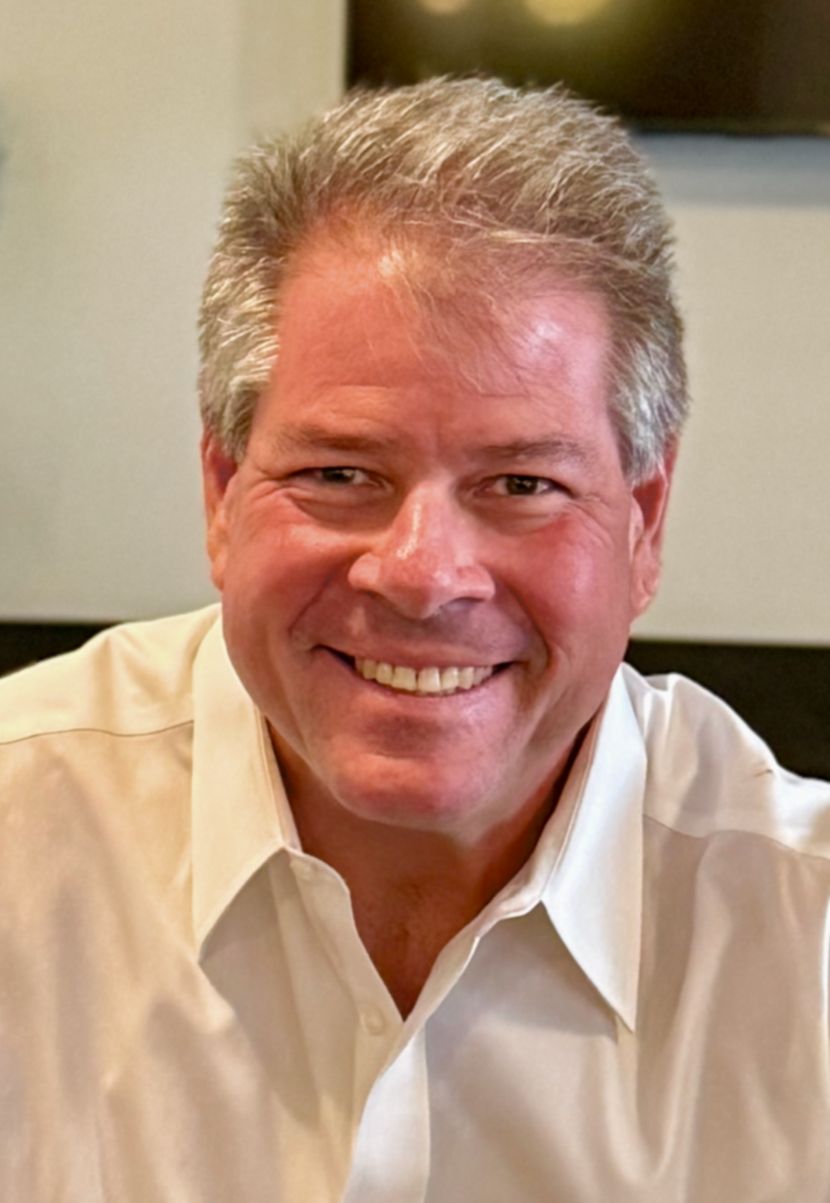 A smiling attorney wearing a white collared shirt.