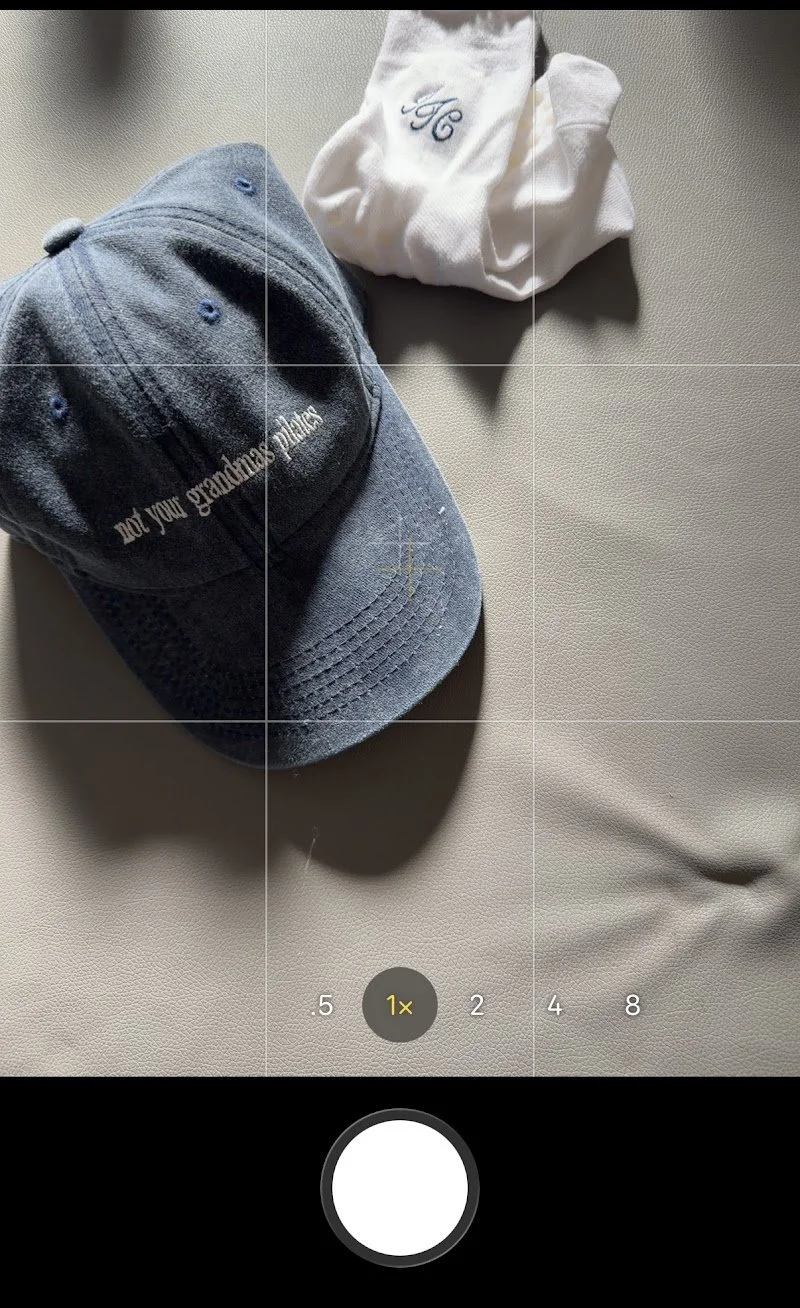 A blue baseball cap with white embroidered text and a white cloth with embroidered initials, placed on a white textured surface.