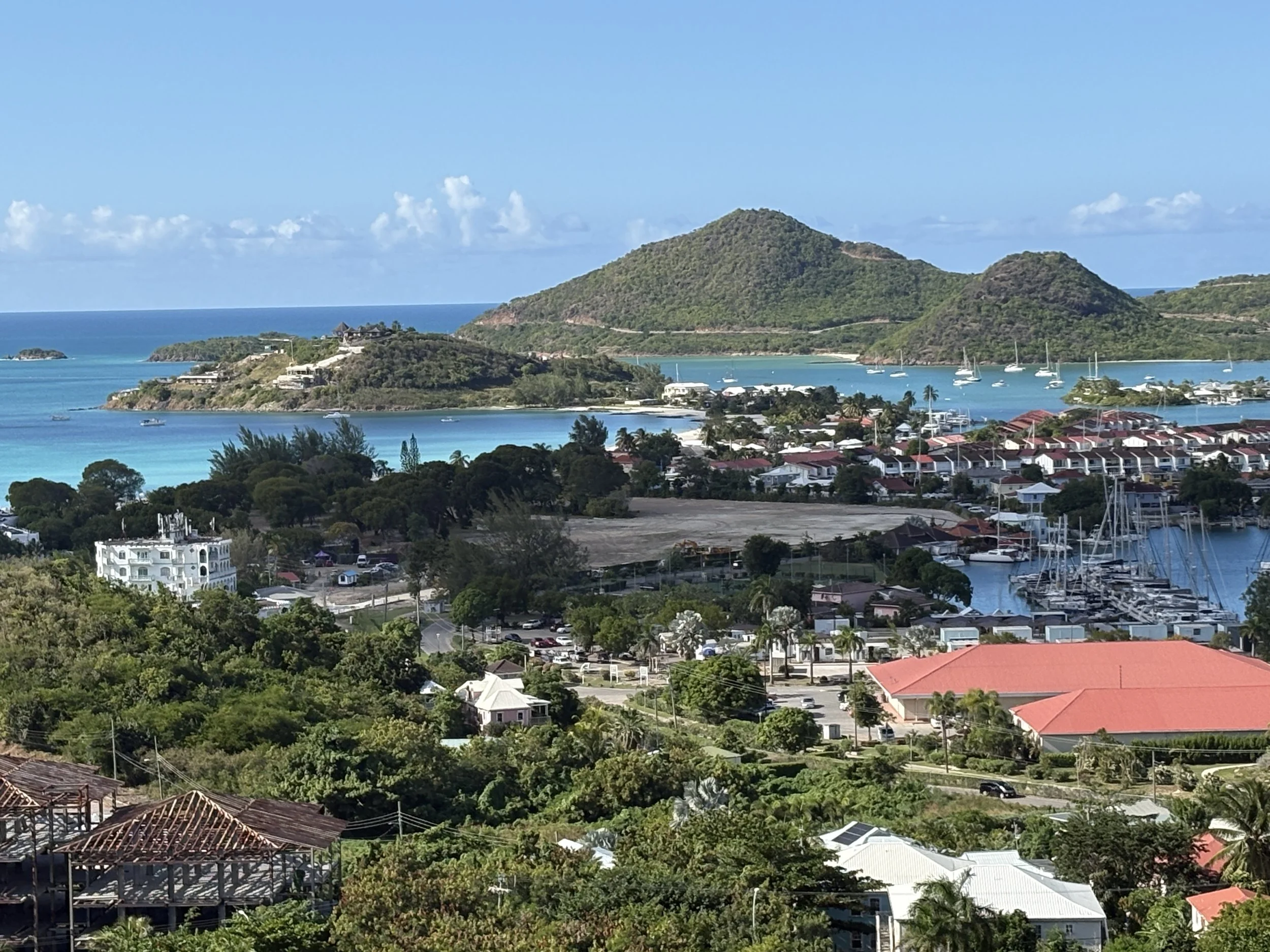 Scenic view of a coastal town with hills, water, boats, and residential buildings with red and white roofs.