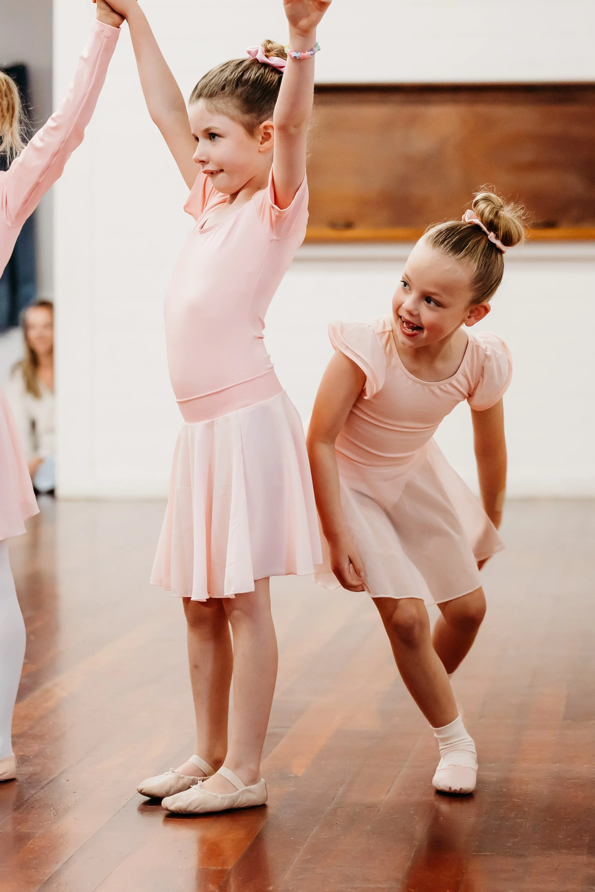 Young ballet dancers one with hands up and the other peeking around the corner