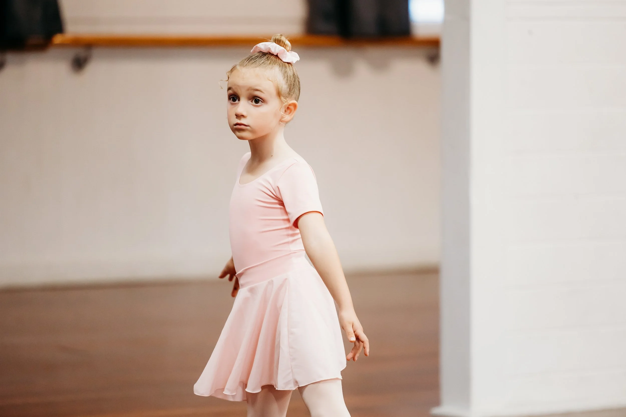 Young dancer in first position ballet academy uniform