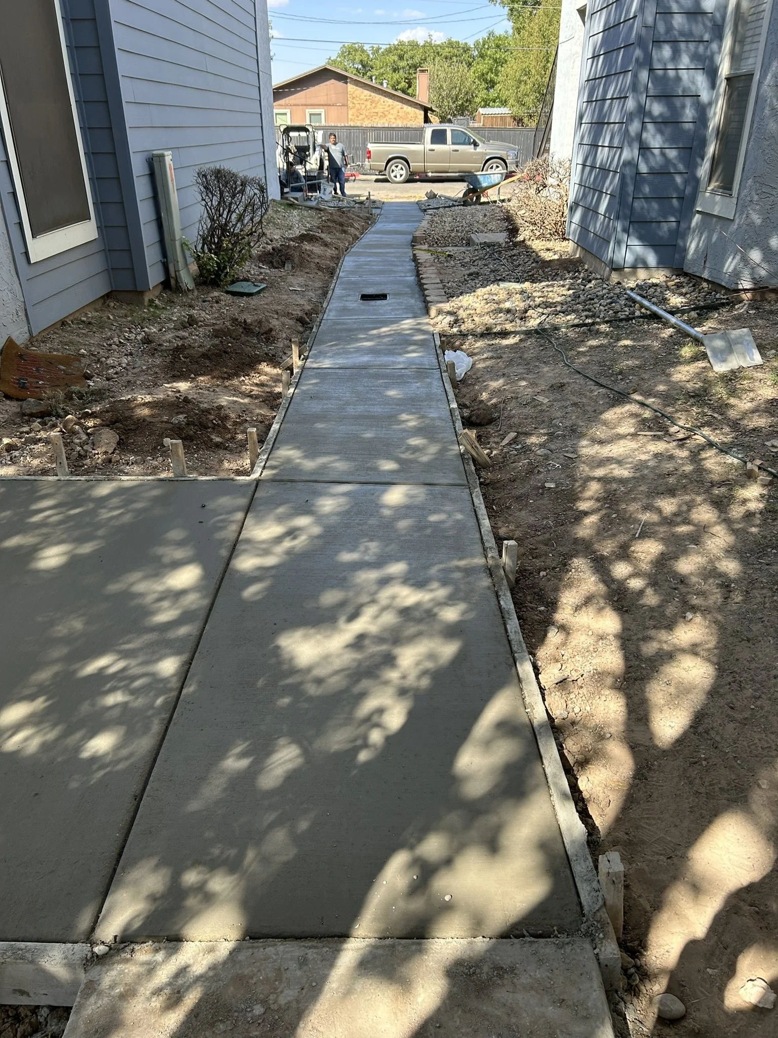 Professional concrete walkway installation between residential properties in Lubbock.