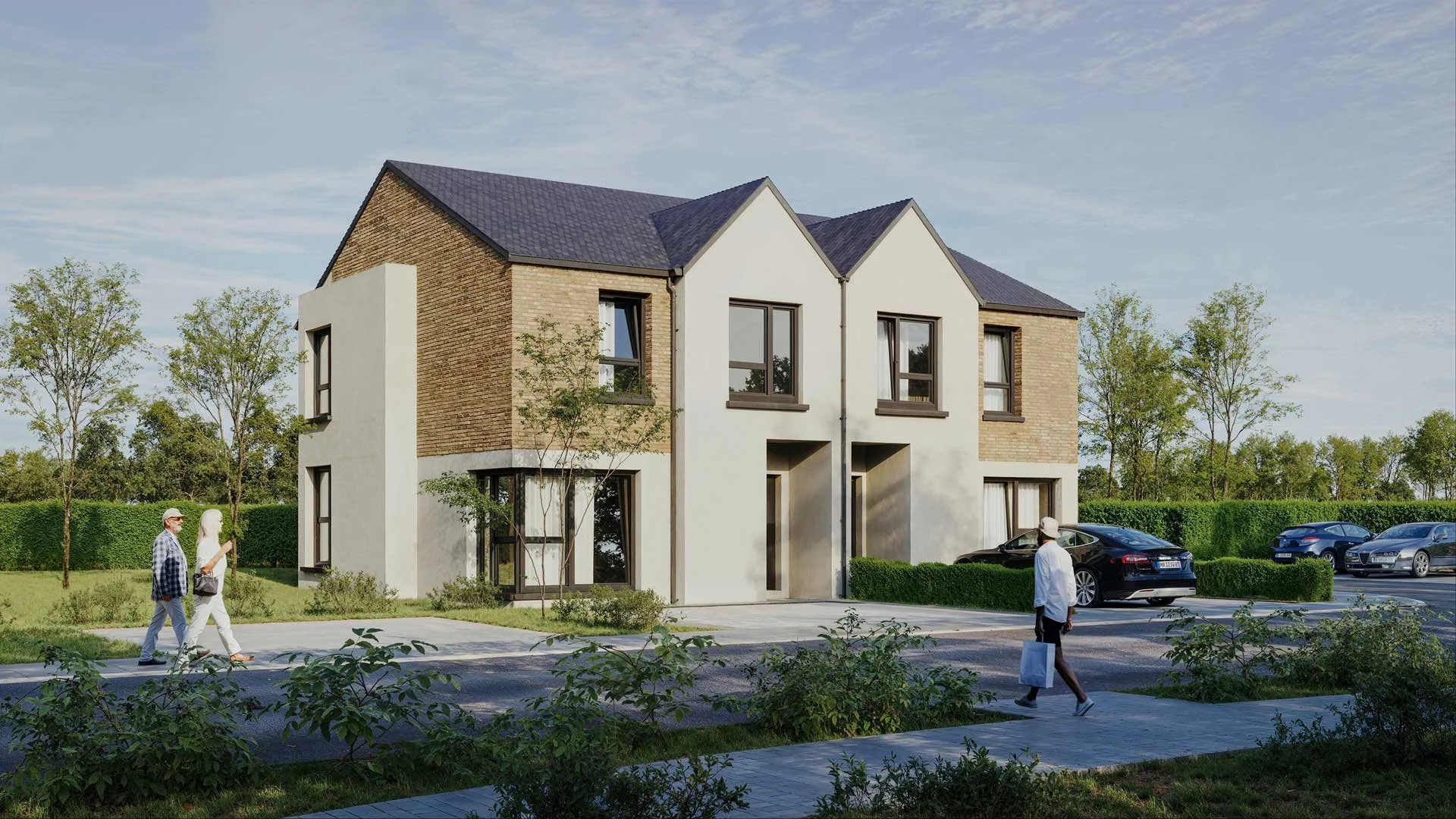A modern townhome with a mix of brick and stucco exterior, surrounded by a landscaped yard. There are trees and shrubs, several parked cars, and pedestrians walking on the sidewalk. The sky is partly cloudy.