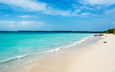 Super bright water and sky with warm sandy beaches. In the distance you see some boats.