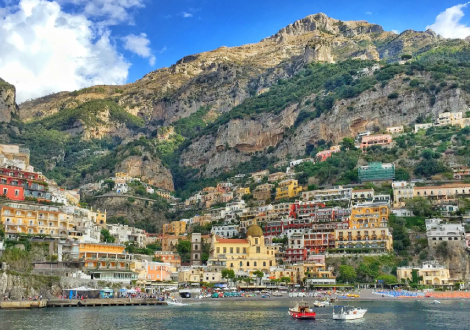 Building line the cliffside of a mountain next to a harbor.