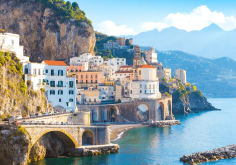 White buildings in a vila and stone bridges and roadways wrap around the coast. 