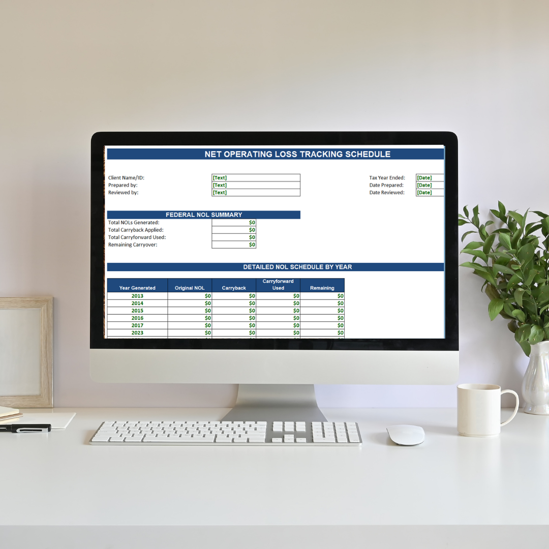 Computer monitor displaying a detailed net operating loss tracking schedule on a white desk with a plant, mug, and framed photo nearby.