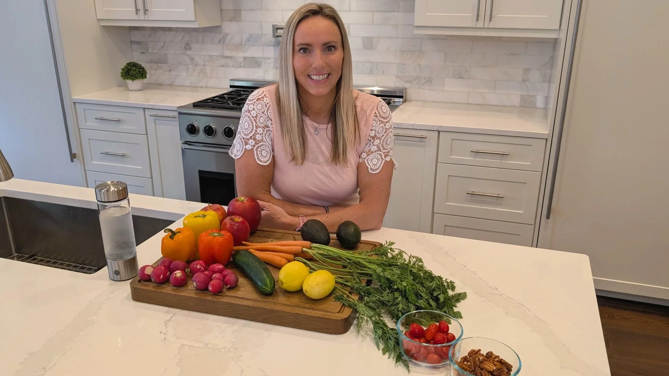 Erin Briley smiling in her kitchen behind a counter filled with fresh produce.