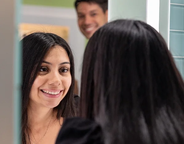 A woman looking into a mirror, reacting to her new smile.