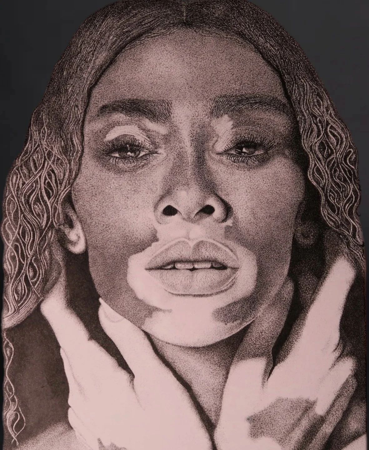 Close-up of a woman with wavy hair, makeup, and her hands touching her face.