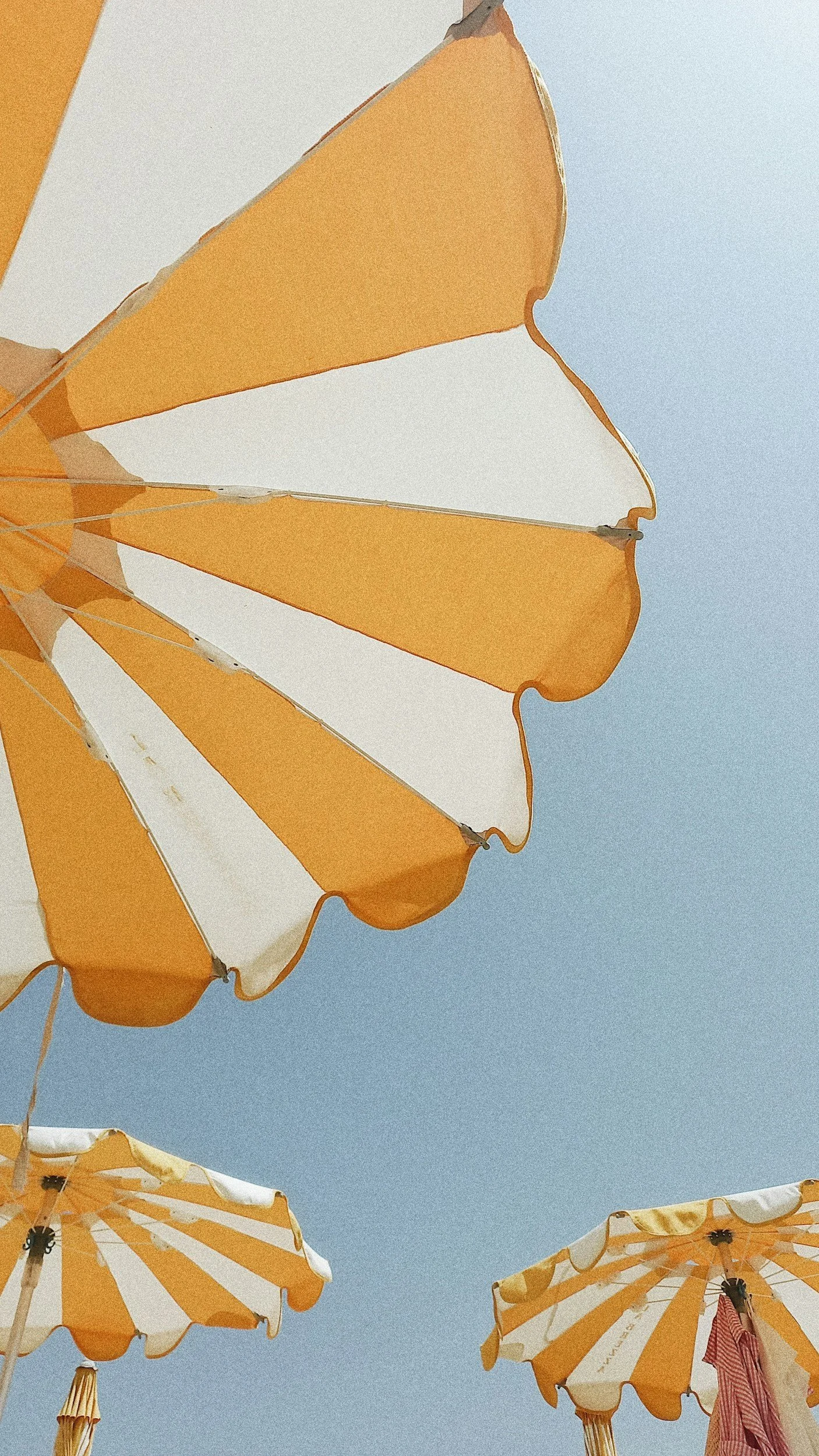 Yellow and white striped beach umbrella against a blue sky
