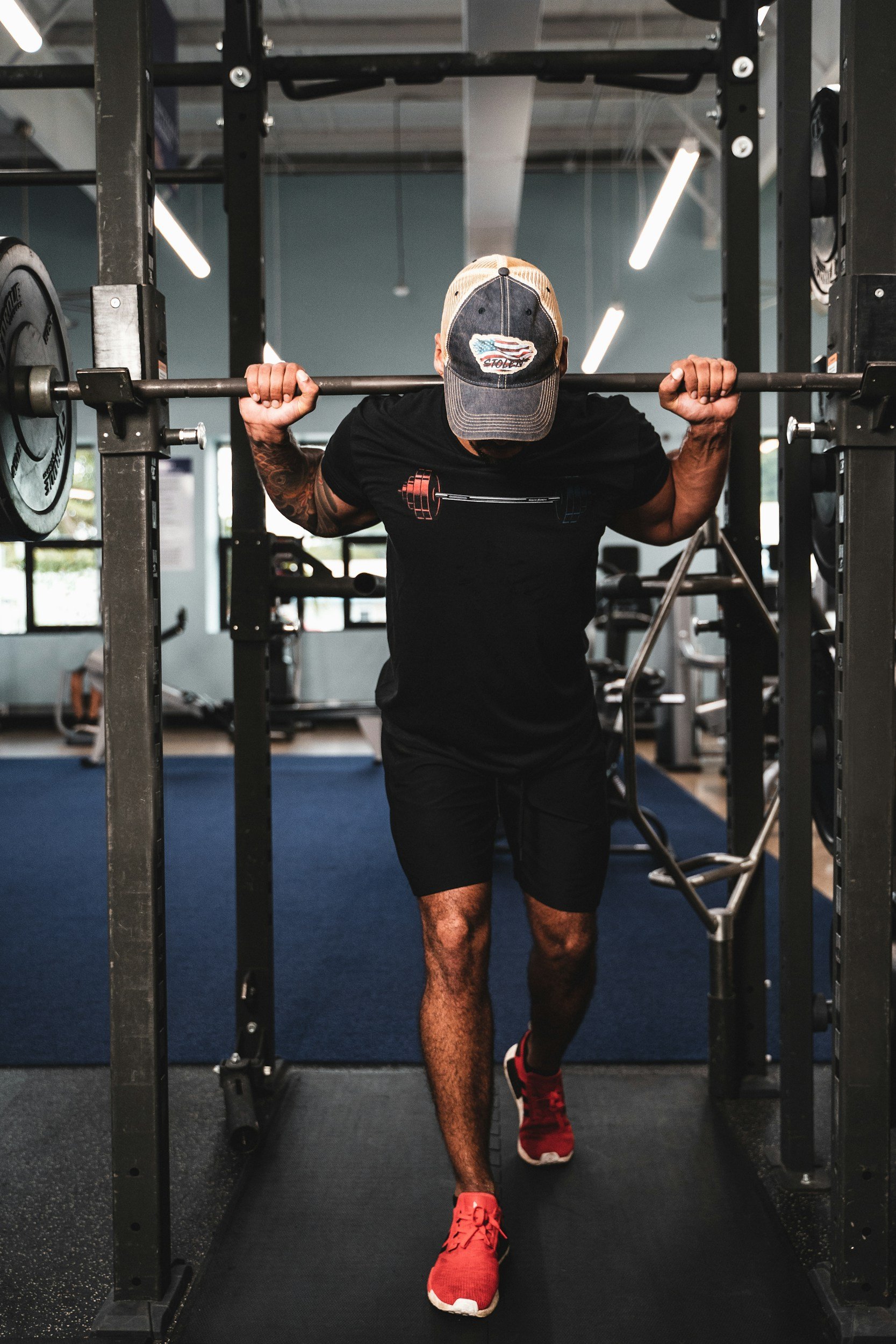 Man working out using a barbell and standing in a squat rack.