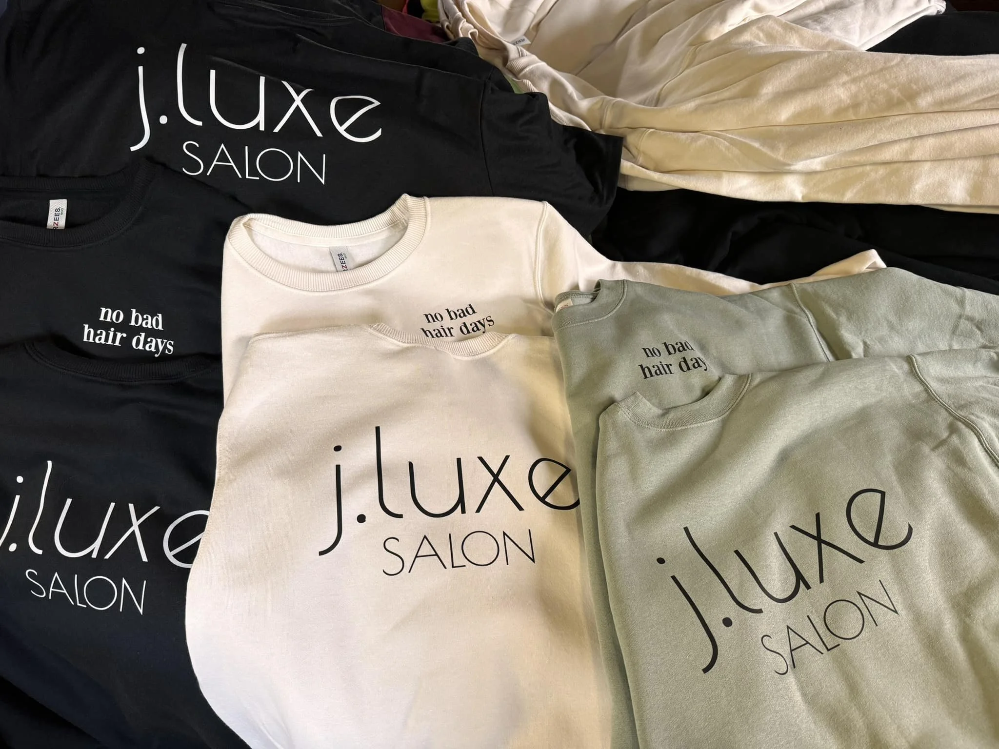 Stack of sweaters from local salon with their logo