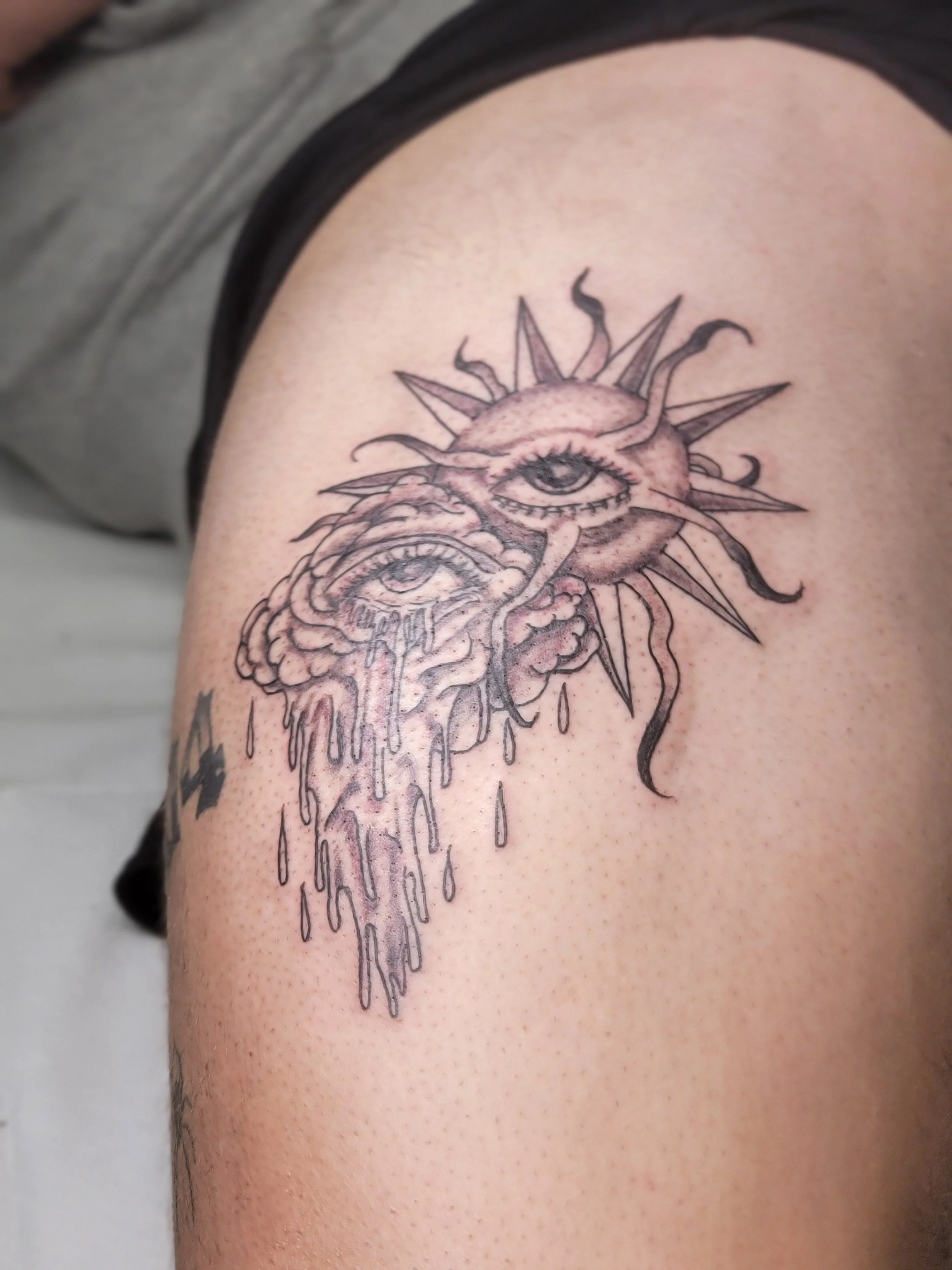 Tattoo of an eye with rays and strings with a melting effect on upper arm.