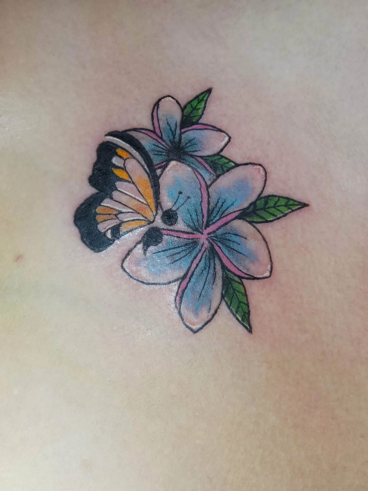 Tattoo of a butterfly and flowers on skin.
