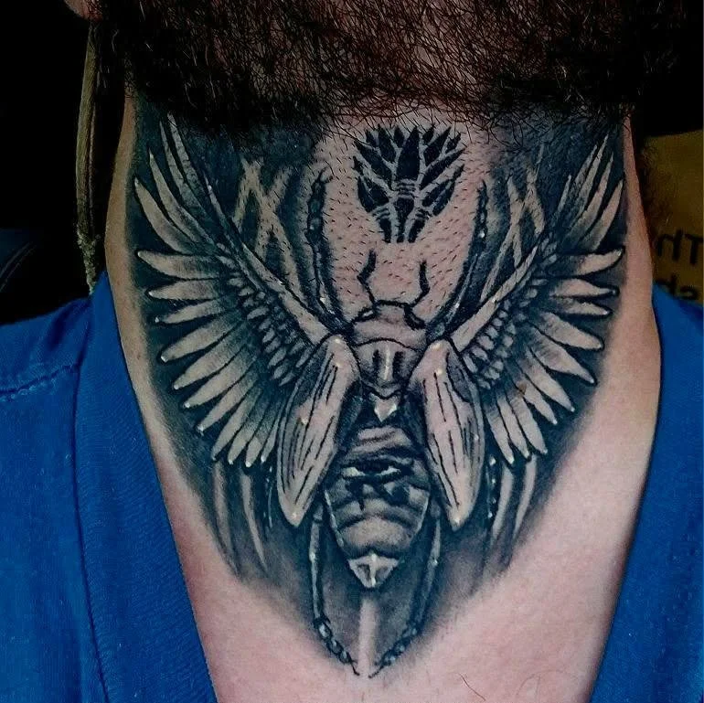 Tattoo of a moth with outstretched wings on a person's chest.