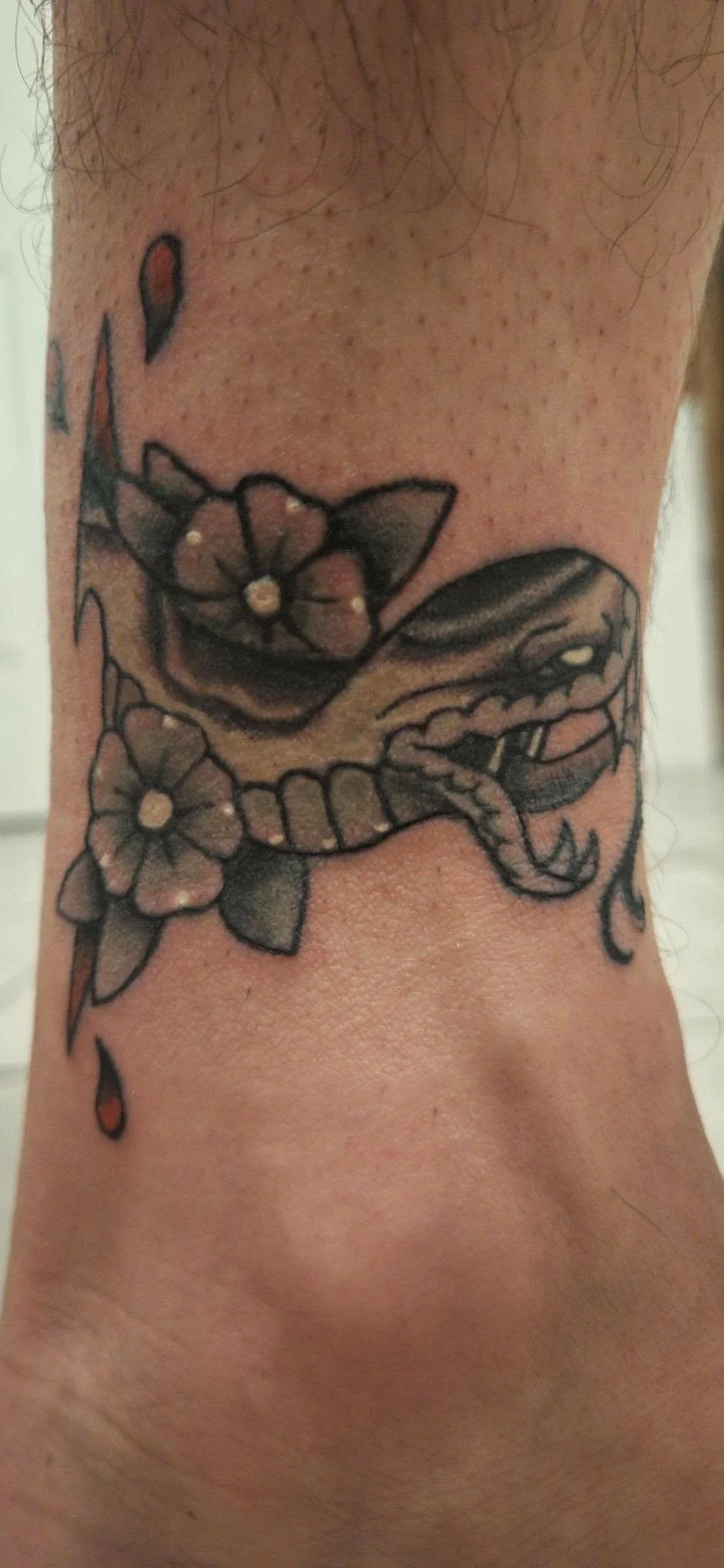 coverup Tattoo of a snake with flowers on skin in traditional style.