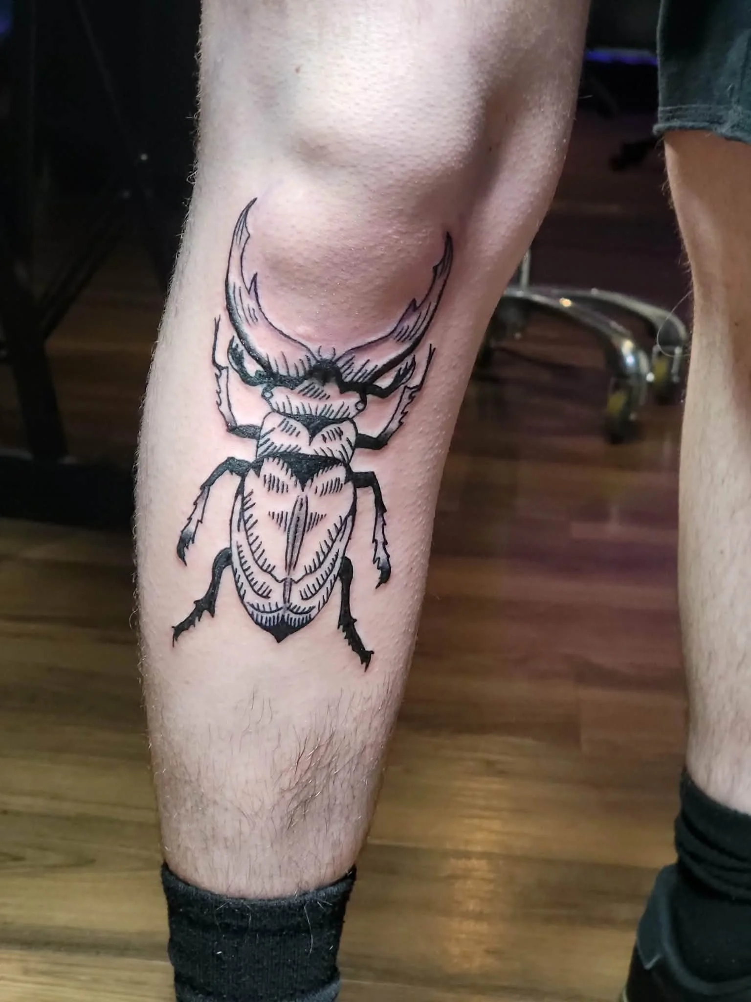 Tattoo of a stag beetle on a person's shin and knee