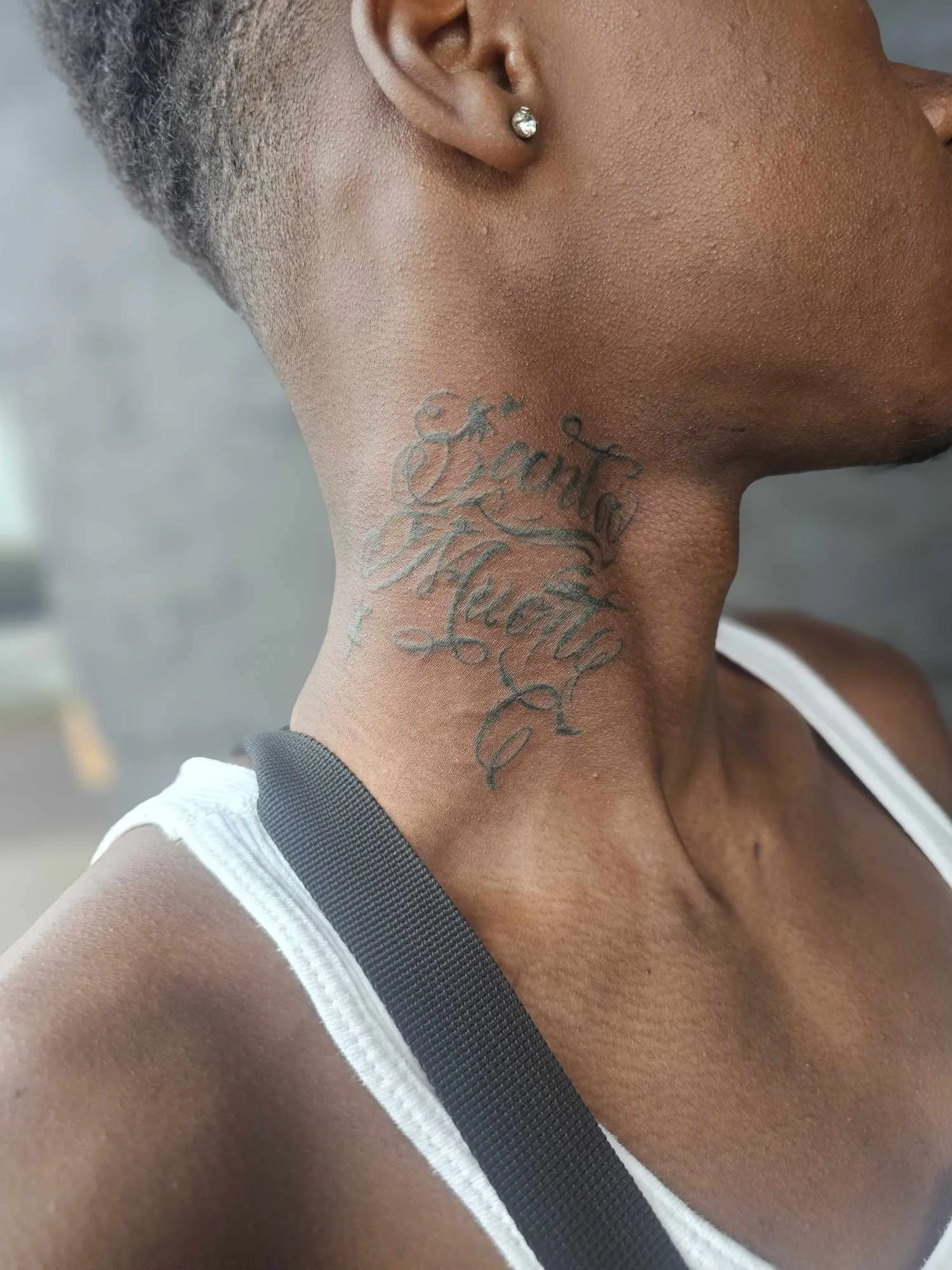Close-up of a person's neck with a script tattoo.