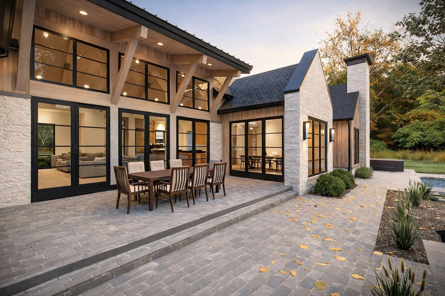 Luxury outdoor living patio at twilight featuring a custom circular stone fire pit, modern chairs, and warm ambient lighting.