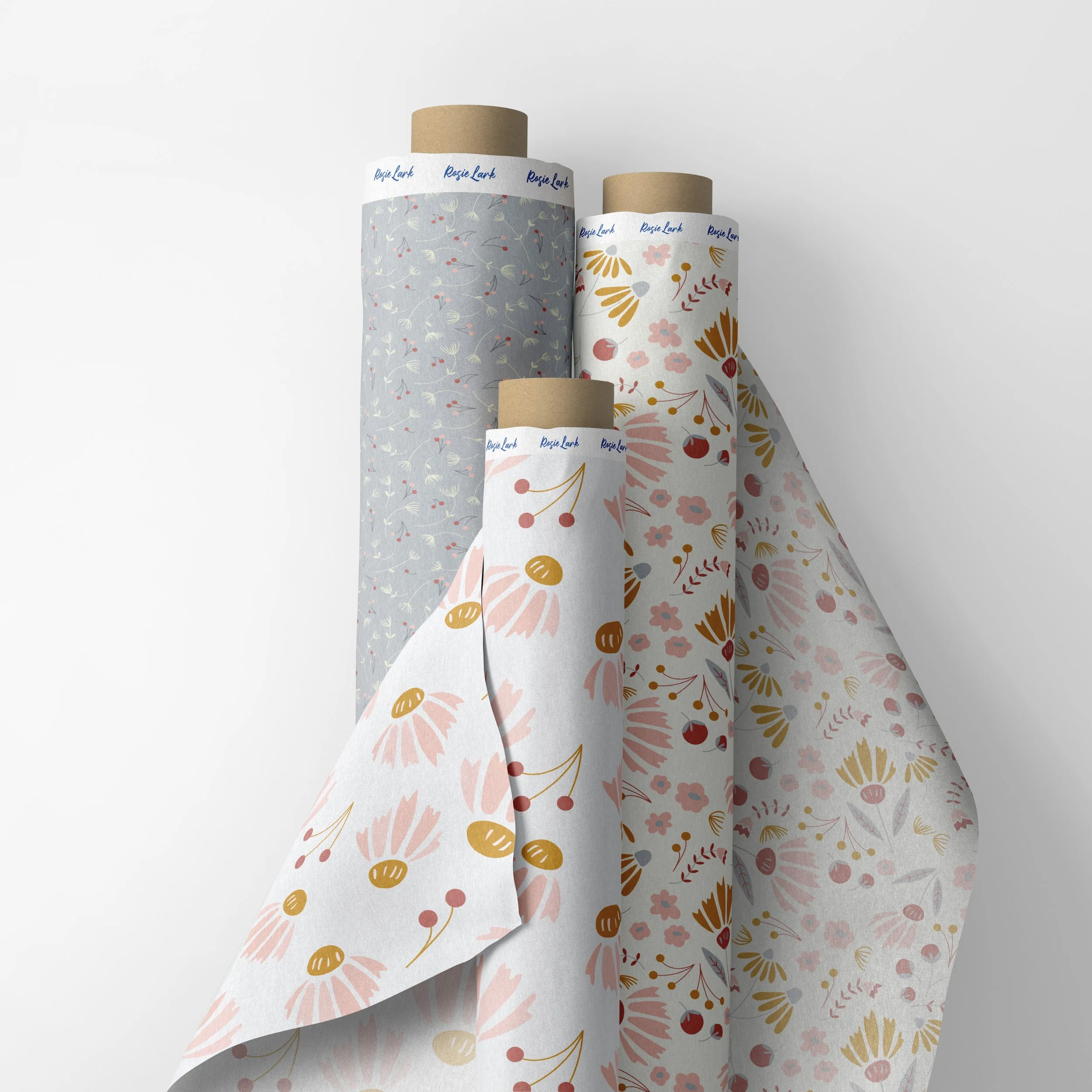 Three rolls of floral patterned wrapping paper with pastel colors and different flower designs standing upright against a white background.