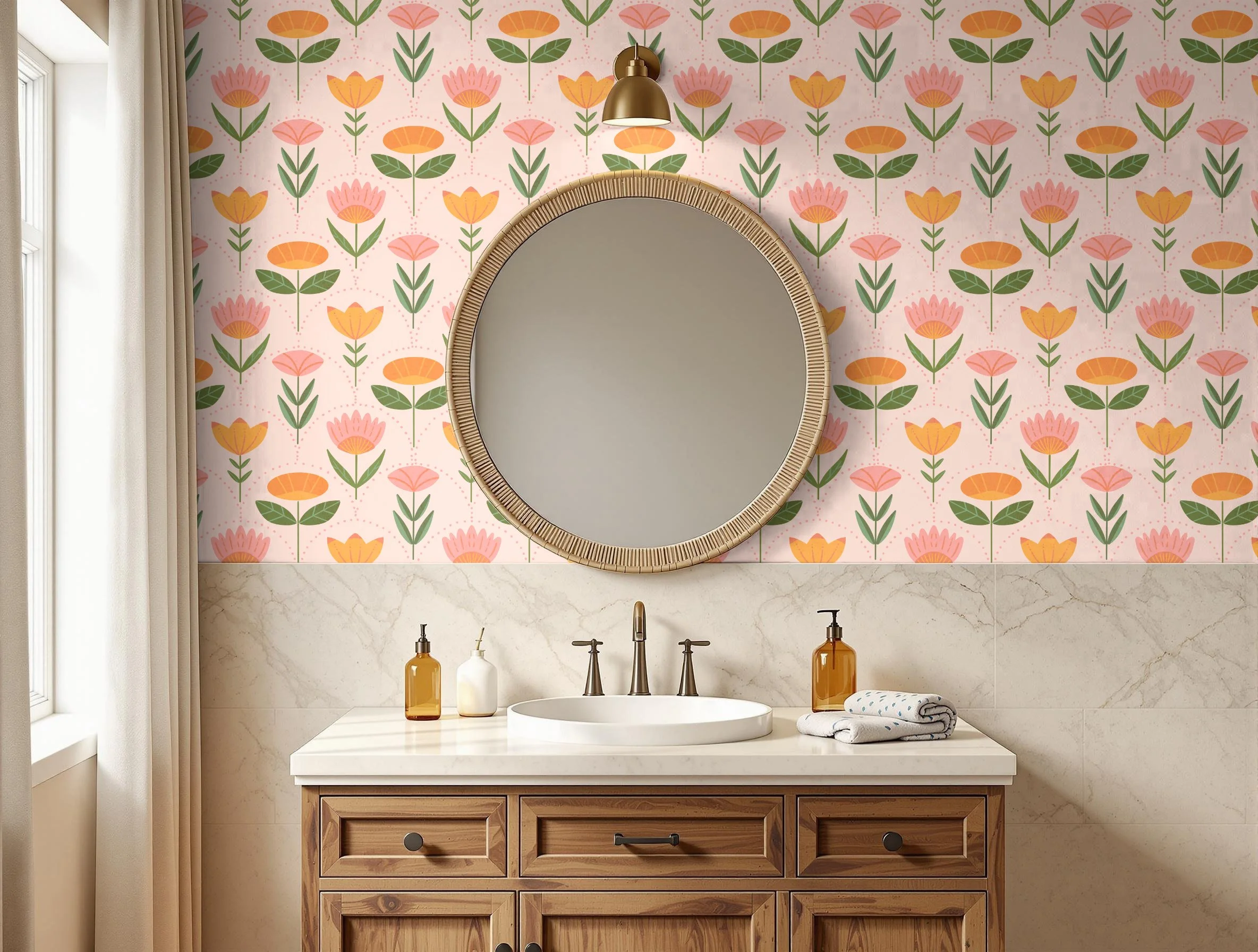 A bathroom vanity with a wooden cabinet, white countertop, and a round mirror. The wall behind has pink floral wallpaper, and there are three bottles on the countertop along with a rolled towel. A window with curtains partially visible on the left. A gold light fixture hangs above the mirror.