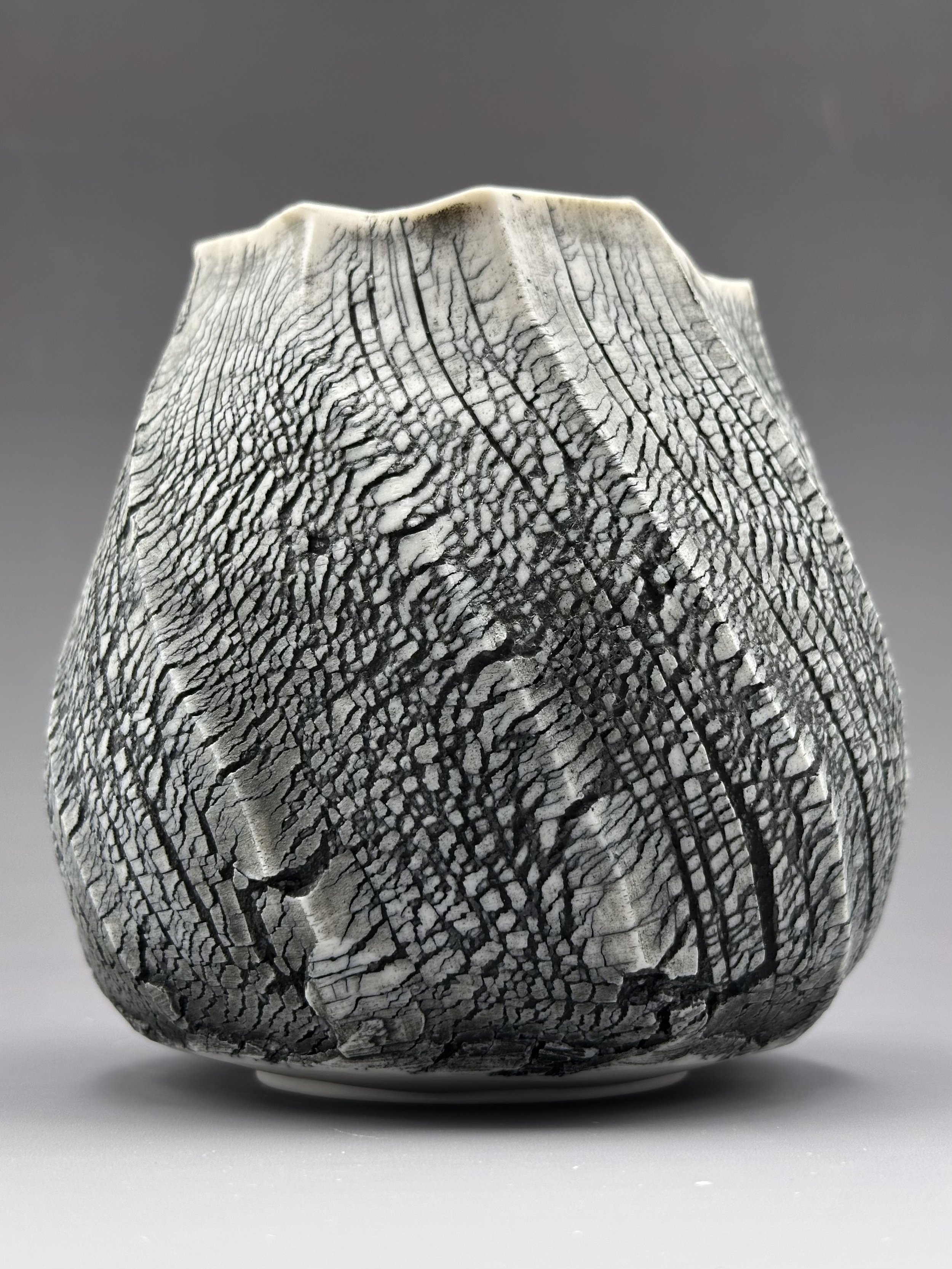 Close-up of a black and white patterned ceramic or stone sculpture with textured, crackled surface and geometric design.