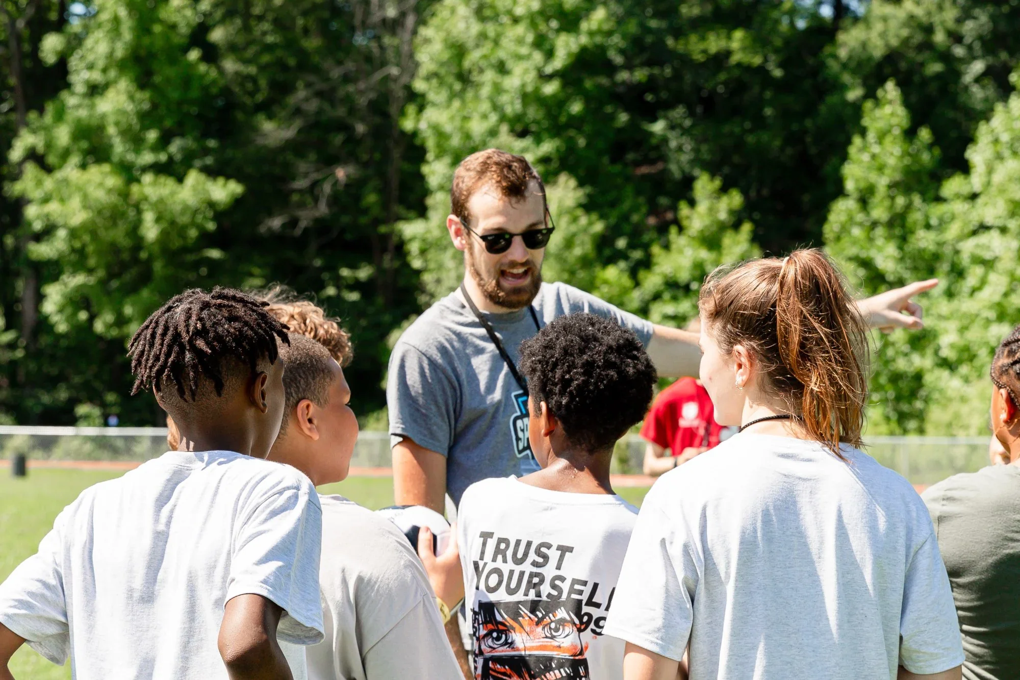 teacher coaching kids outdoors