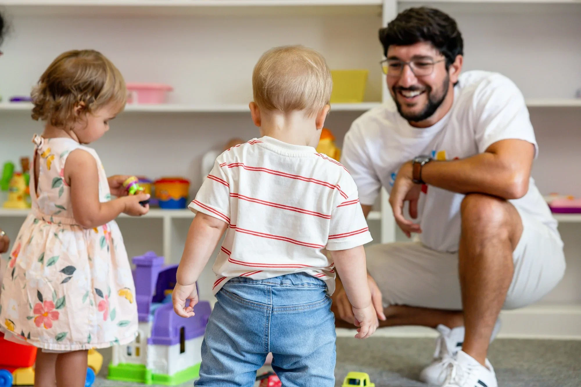 teacher smiles at kids playing with toys