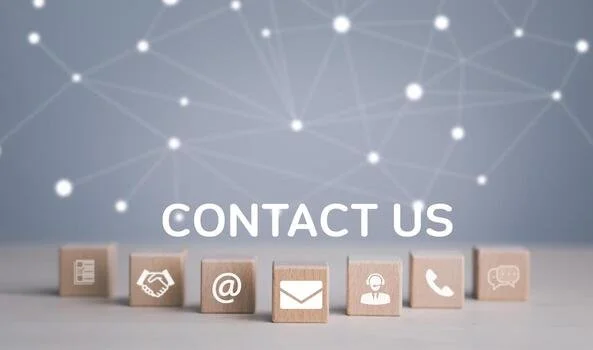 A row of wooden blocks with contact icons, including a business card, handshake, email, person, phone, and chat bubble, with 'Contact Us' text above and a digital network background.