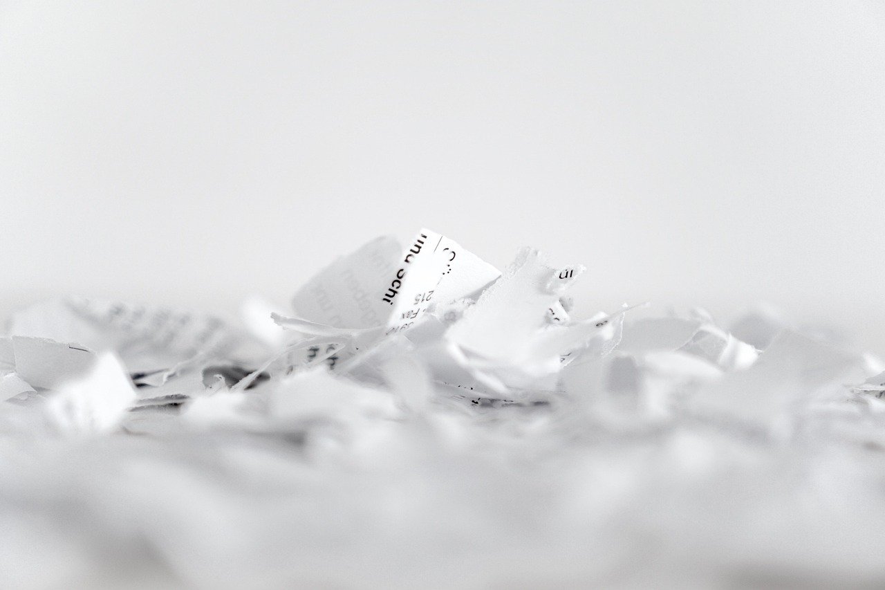 Crushed pieces of white paper scattered on a white surface.
