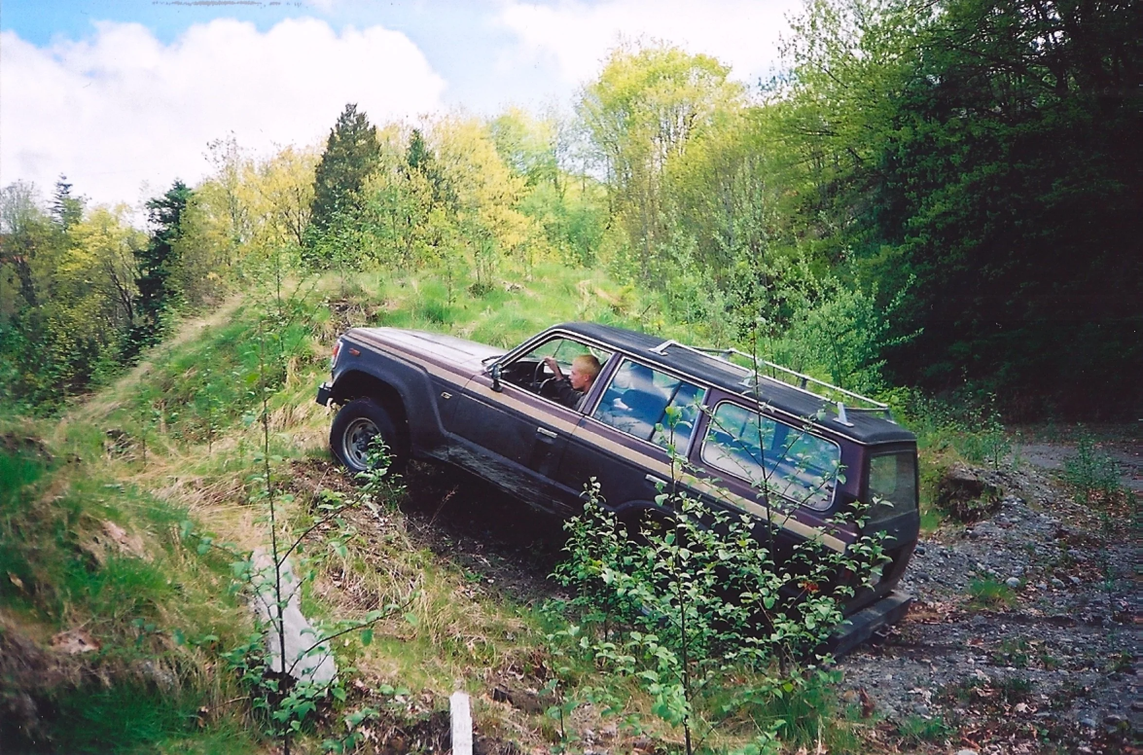 Brown 1982 BJ60 Landcruiser driving up a dirt hill.